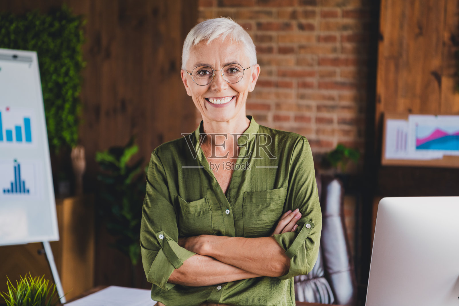 迷人可爱的女士穿着衬衫，佩戴眼镜，坐在工作场所的阁楼室内。照片摄影图片