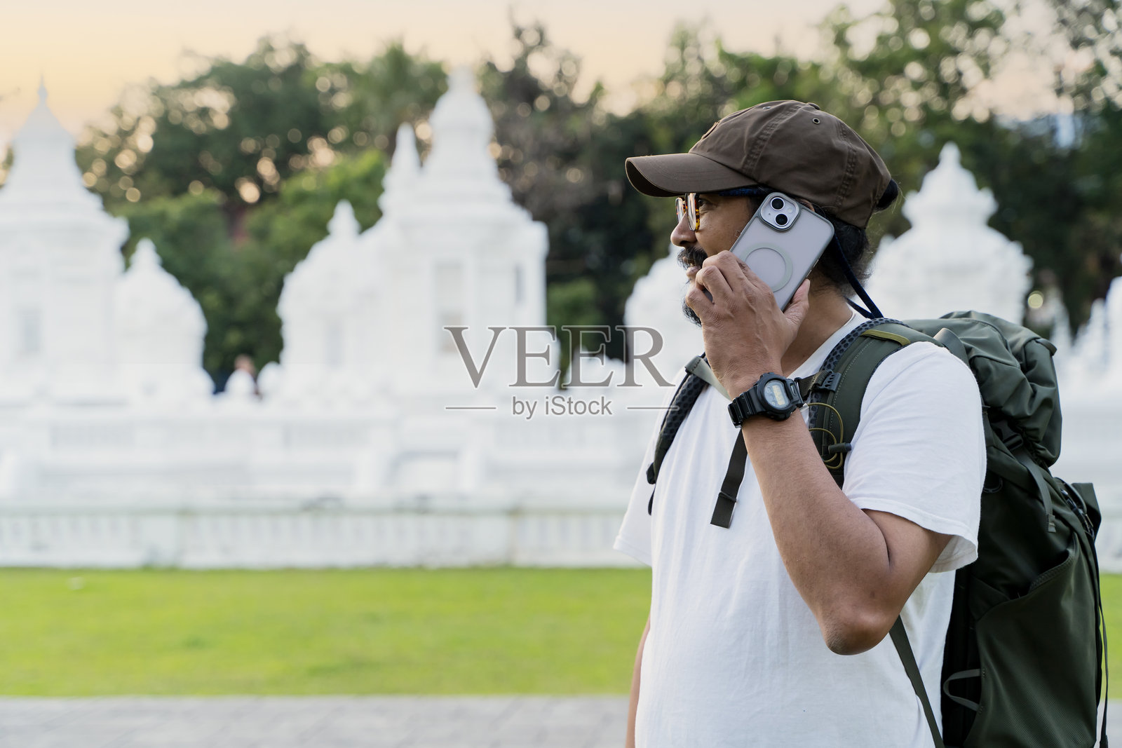 白人灰发男游客通过智能手机与朋友进行远程对话。照片摄影图片