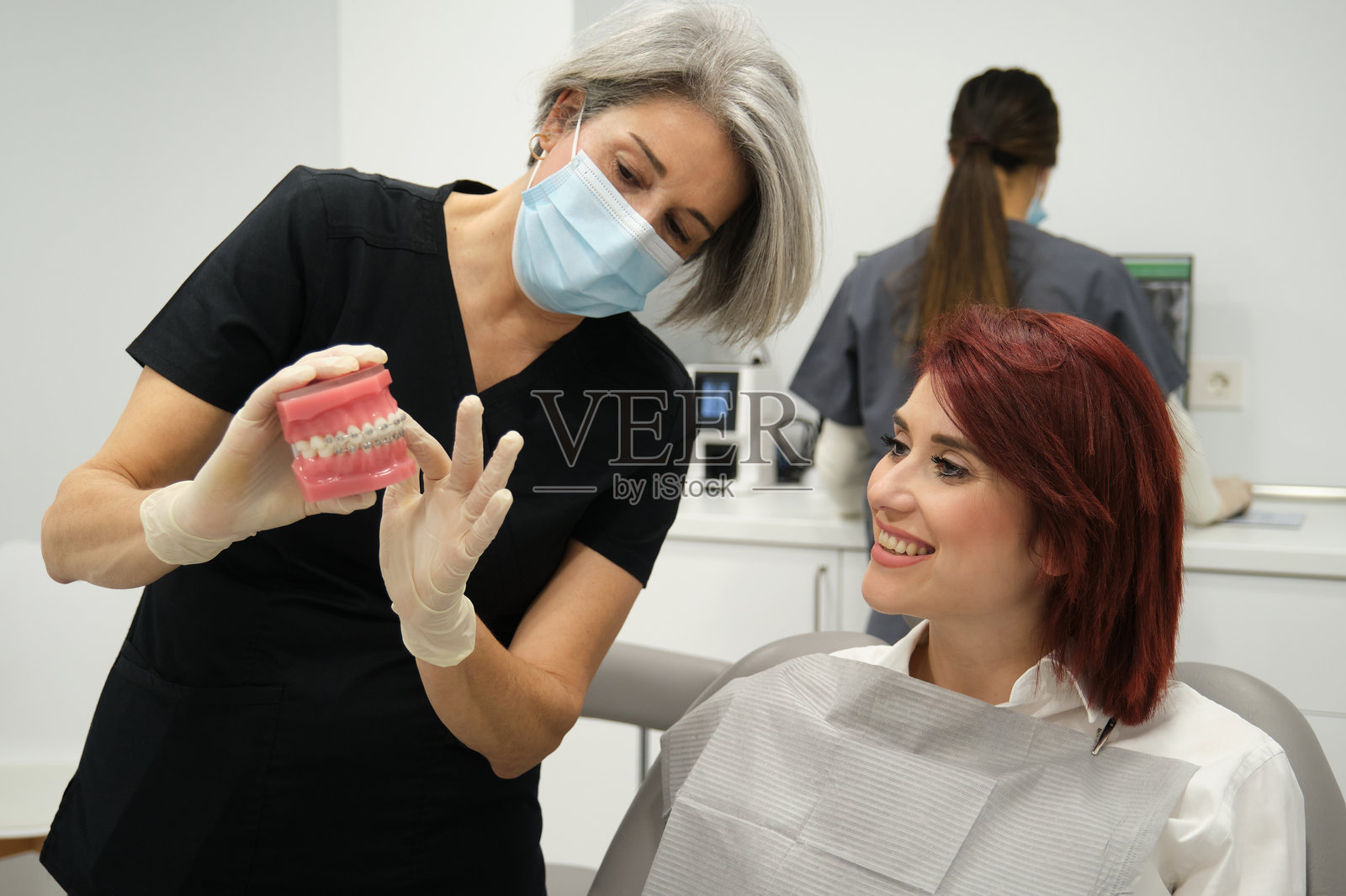 牙医使用牙模向患者解释牙套。照片摄影图片