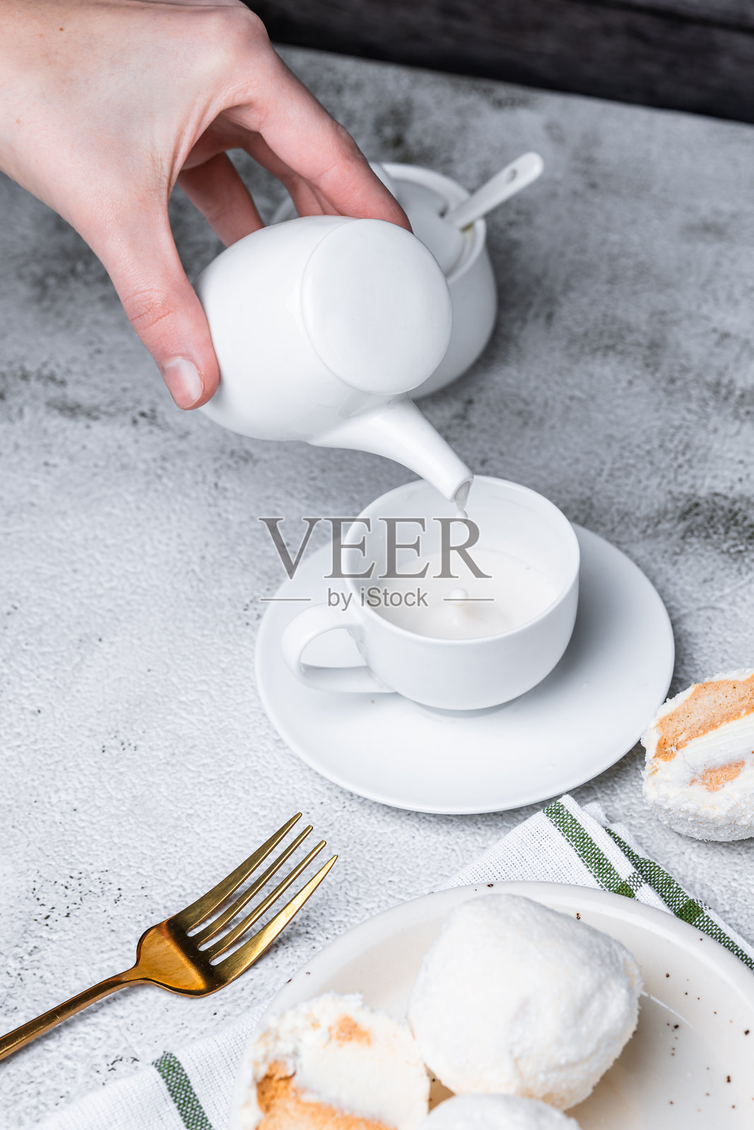 女性手将牛奶倒入一杯加了棉花糖的咖啡中照片摄影图片