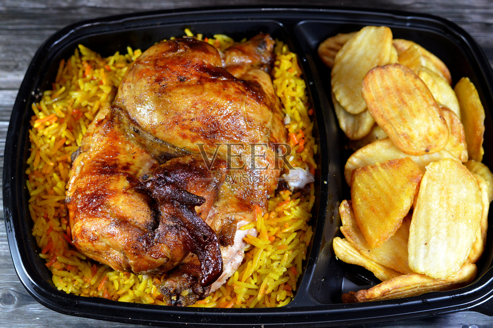 叙利亚阿拉伯美食：机器烤制的烧烤鸡肉，配以五彩的巴斯马蒂米饭和炸薄薯条，盛放在黑色一次性盘子中。照片摄影图片