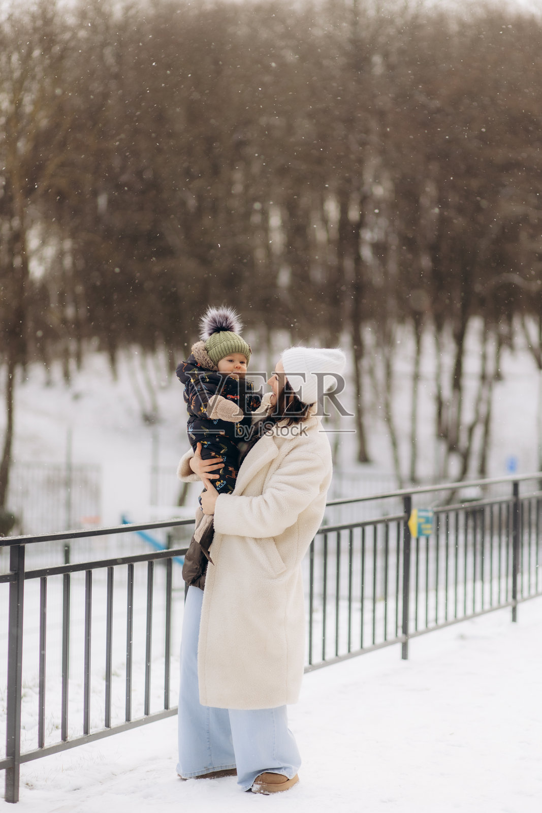 一位快乐的母亲与她的儿子在冬季自然中散步照片摄影图片