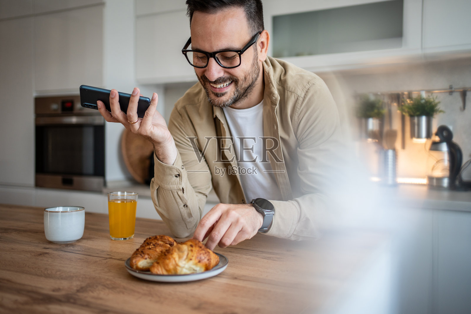 男人一边打电话一边享受他的可颂面包照片摄影图片