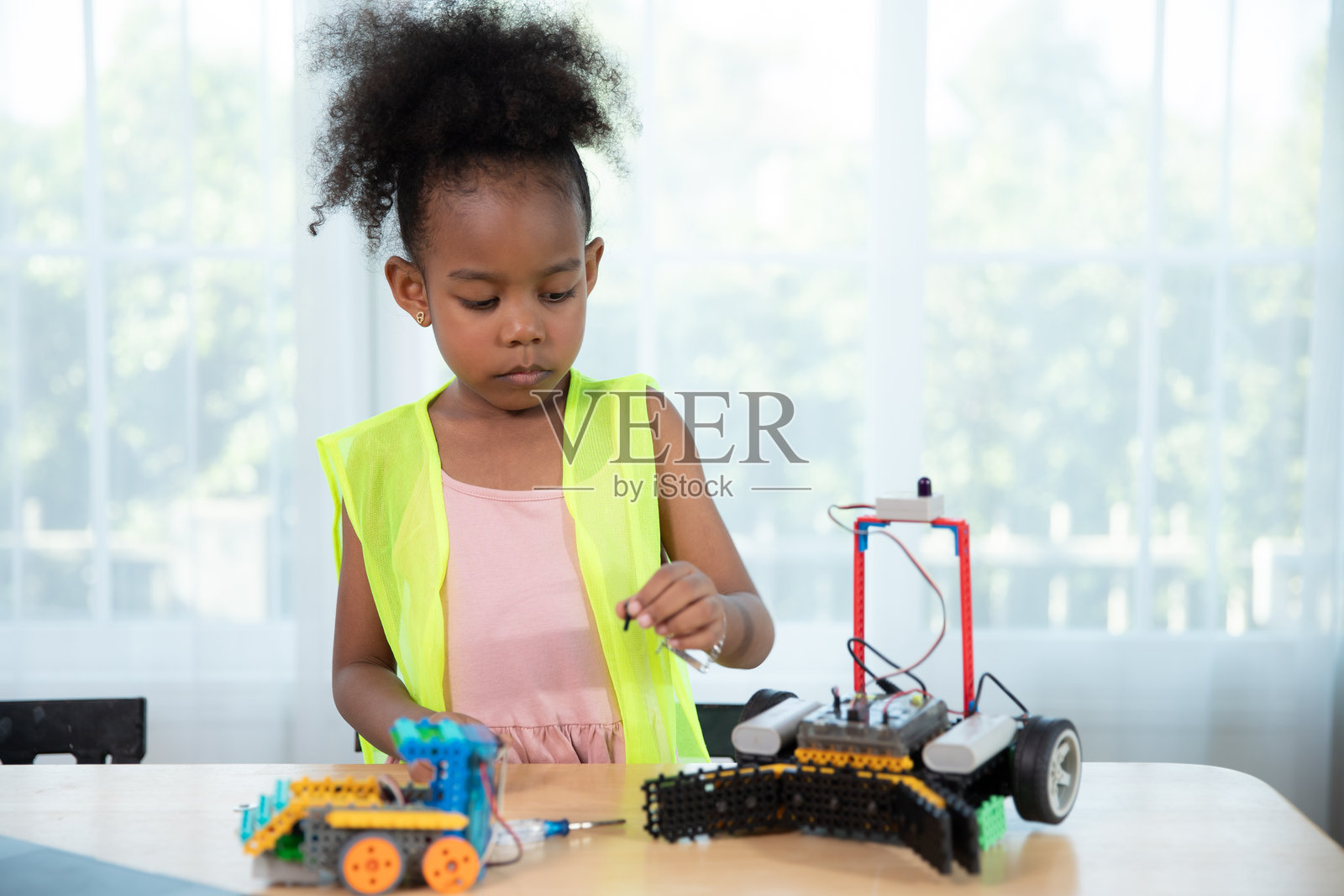 年轻女孩在机器人编程课上进行机器人设计。使用构造块和笔记本电脑进行STEM教育，促进学校孩子的科技教育发展。照片摄影图片