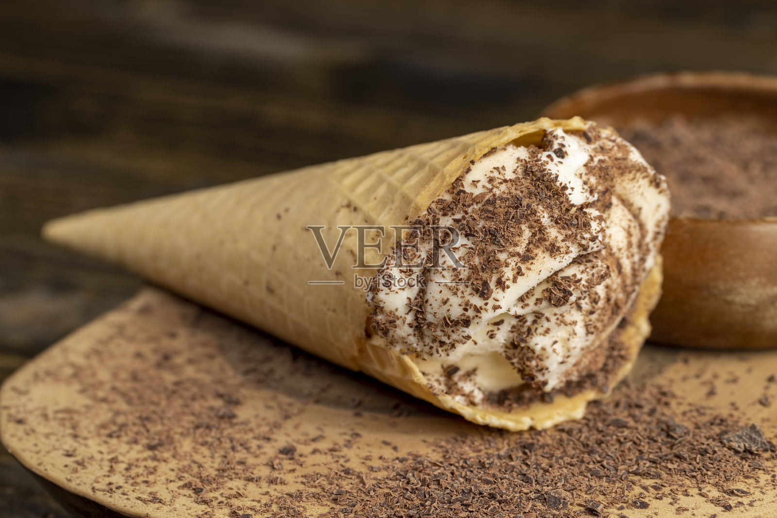 桌子上放着奶油白色的冰淇淋，上面有巧克力碎片。照片摄影图片