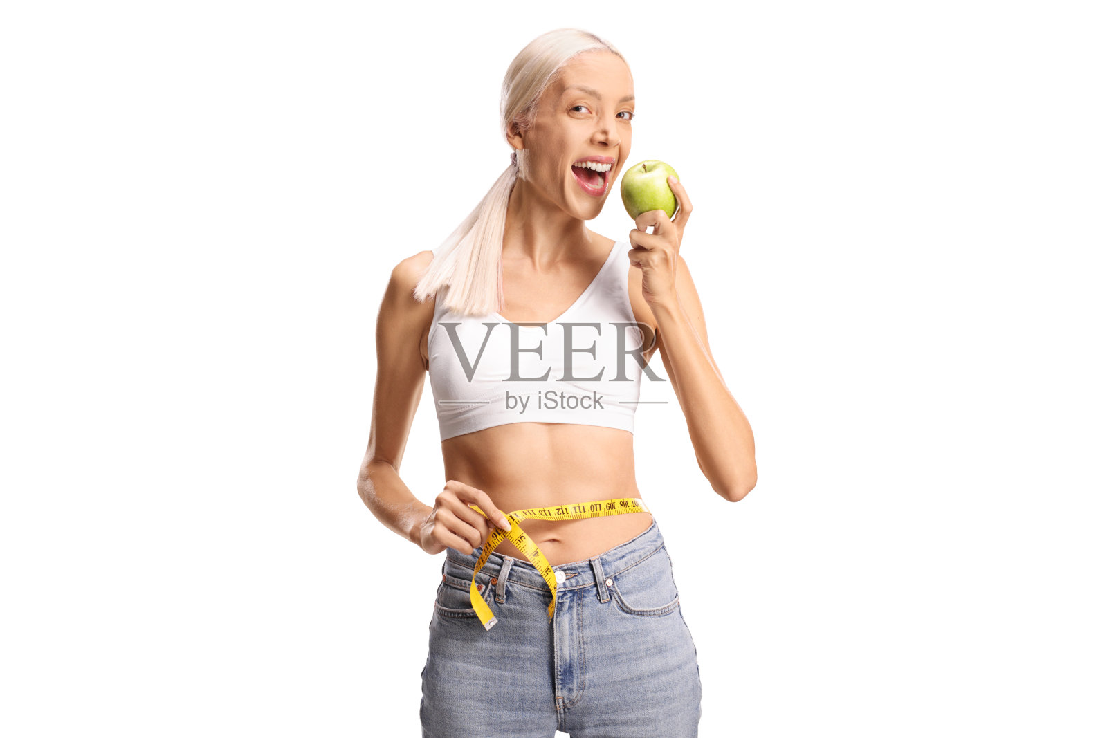 瘦女人用卷尺围绕腰部，正在吃一个绿色苹果照片摄影图片