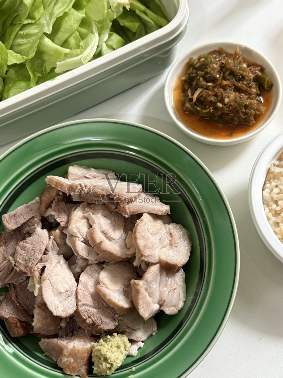 嫩滑的包饭，韩国煮猪肉五花肉，搭配新鲜生菜、大蒜和酱料。这道美味可口的菜肴非常适合在传统韩国餐中包裹和分享。照片摄影图片