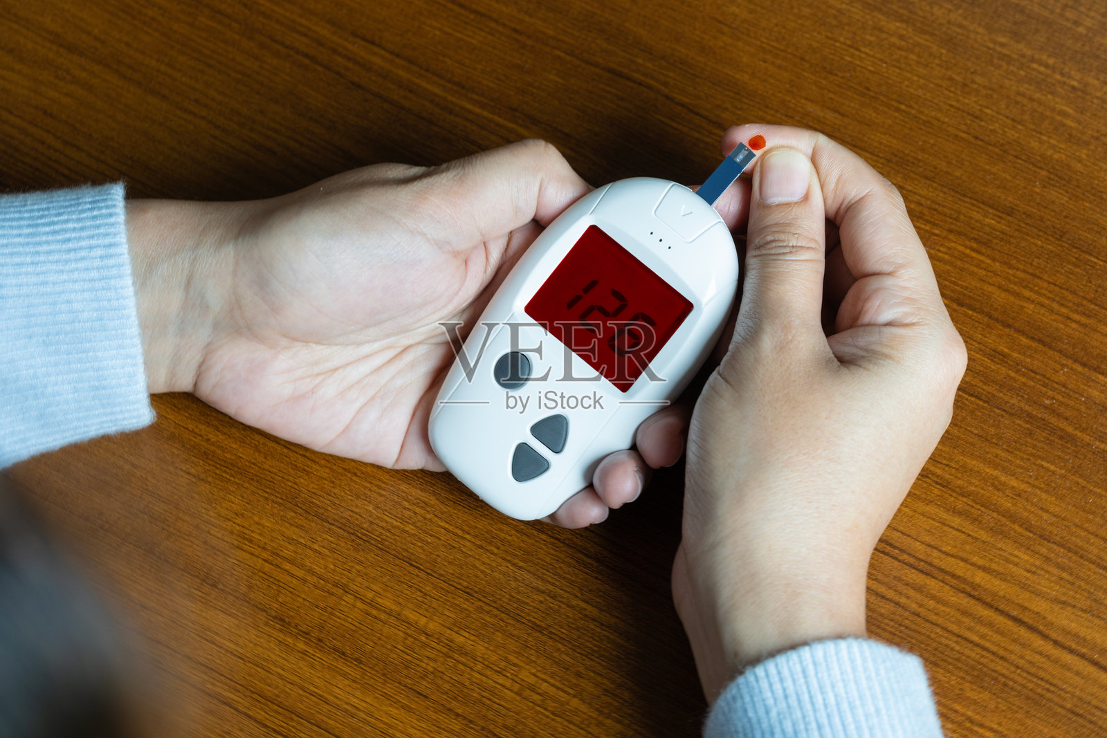 一名女性在他的手指上抽血并测试糖尿病。使用数字血糖测试仪检查高血糖水平。健康护理和医疗概念照片摄影图片