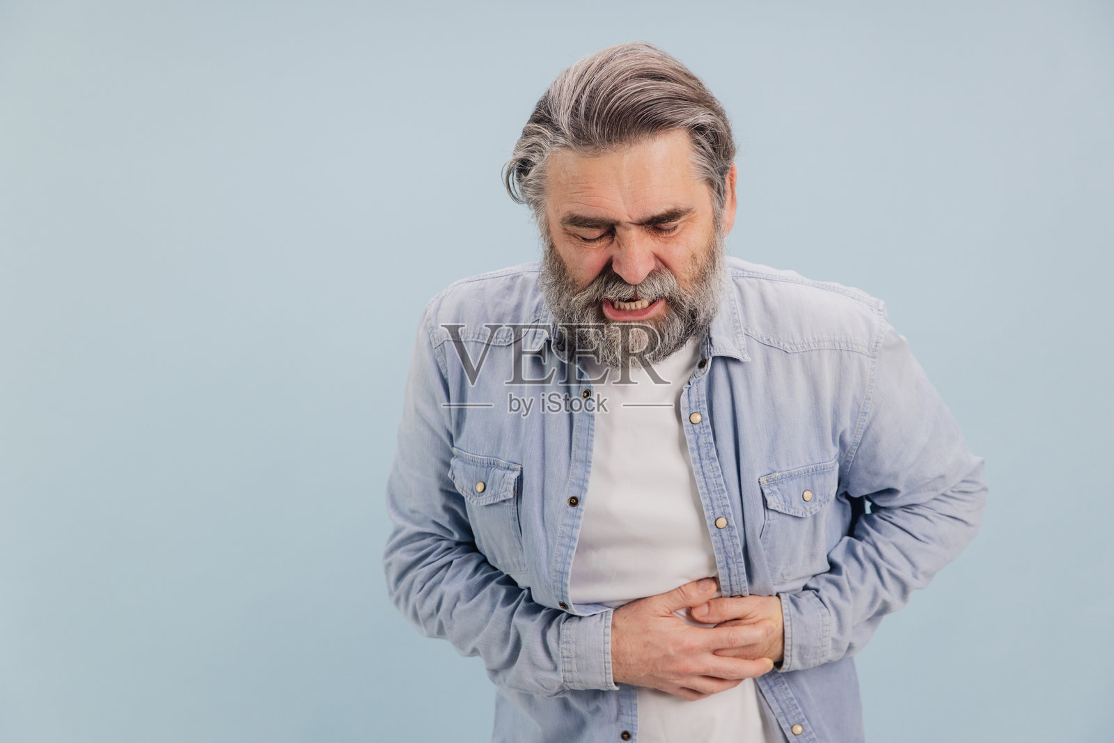 蓝色背景下腹痛的老年男性照片摄影图片