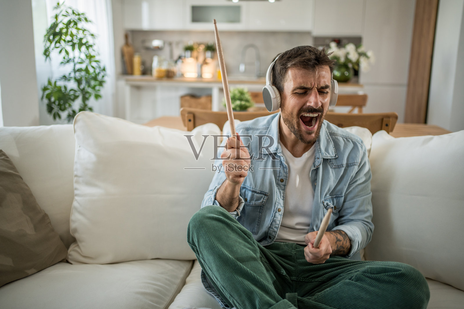 戴着耳机的年轻人正在演奏想象中的鼓。照片摄影图片