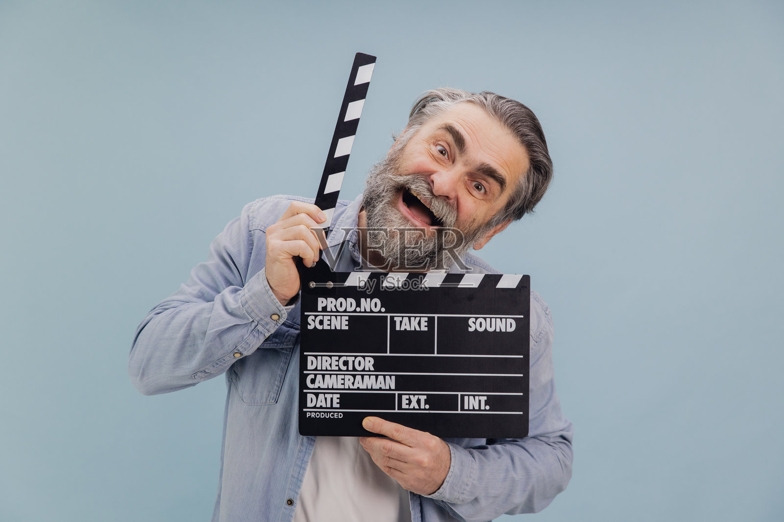 兴奋的资深电影导演手持电影拍板，微笑着享受乐趣照片摄影图片