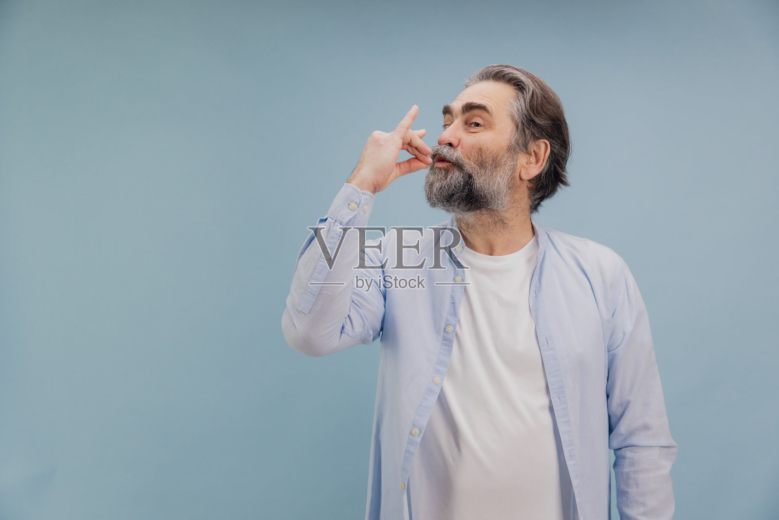 老年男子在蓝色背景下送吻照片摄影图片