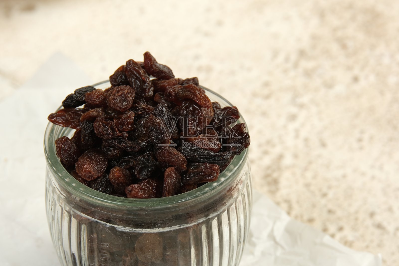 近距离看，玻璃罐里的黑葡萄干，孤立在白色的背景上，照片摄影图片