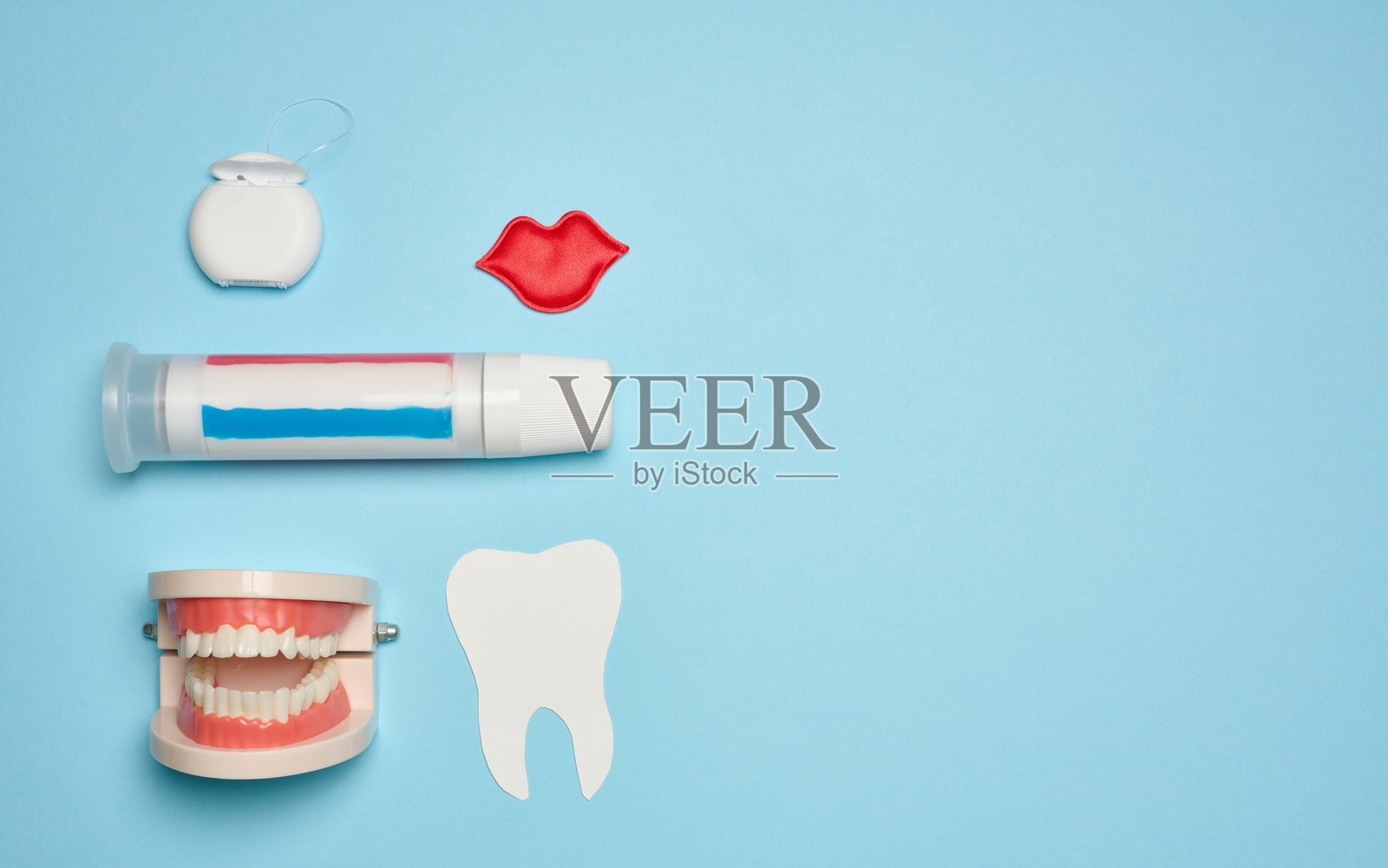 人类下巴的模型，白色的牙齿，牙线和牙膏在蓝色的背景，俯视图。照片摄影图片