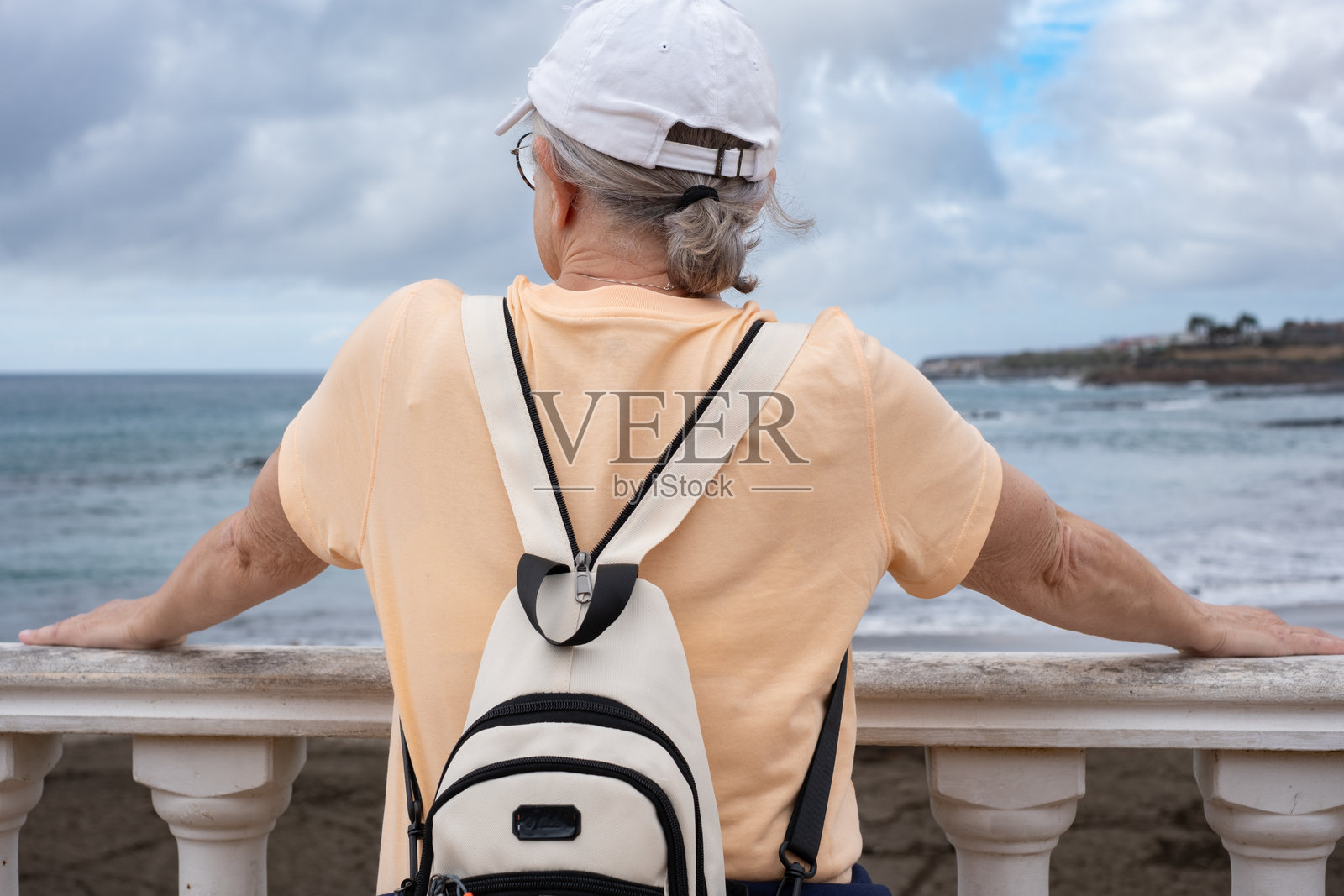 背影的白人成熟的女性游客在假期中面朝大海，欣赏海浪，享受户外的自由和健康生活方式。照片摄影图片