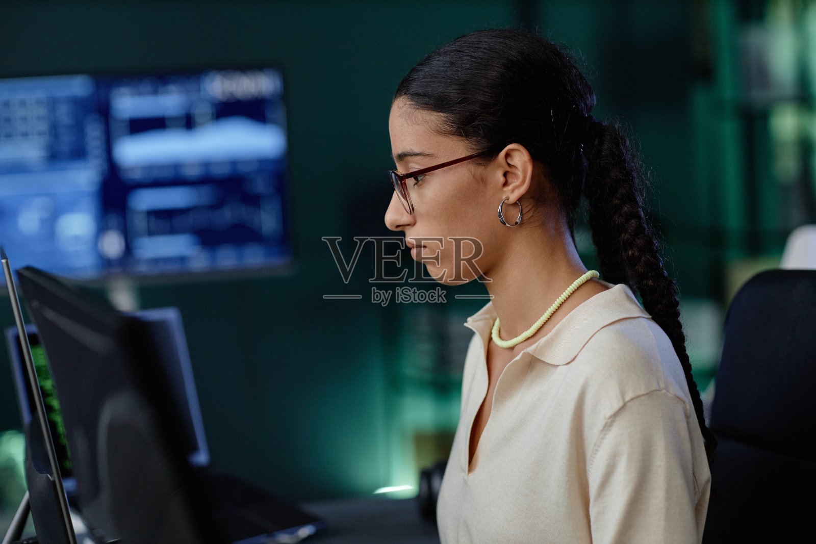 中东女性程序员在工作场所使用电脑，佩戴时尚耳环的个人资料照片摄影图片