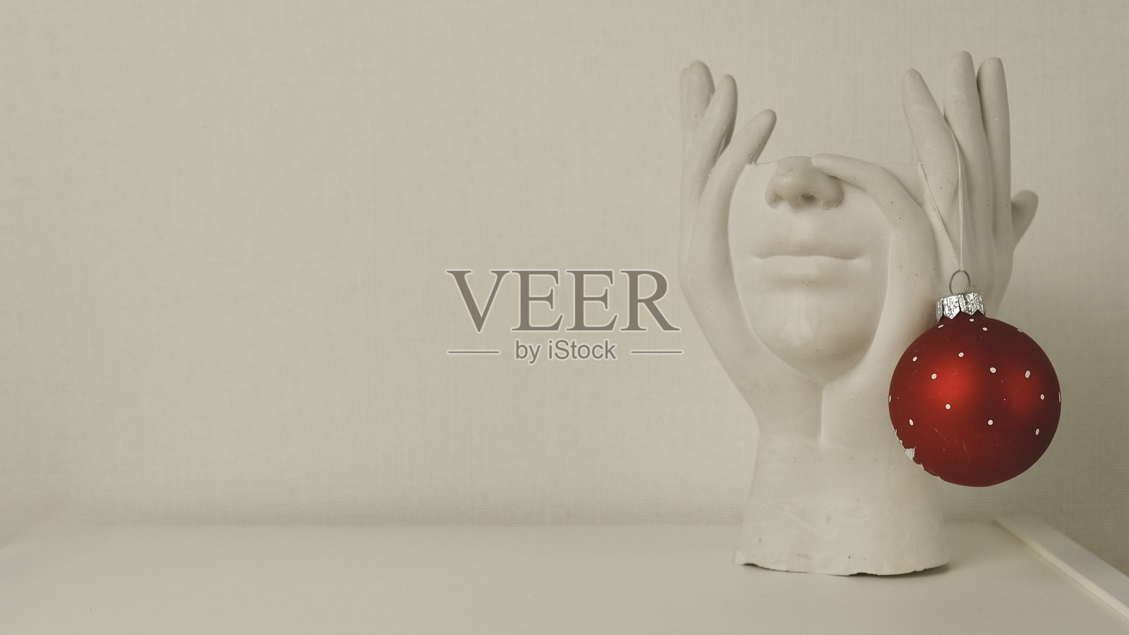 白色背景上的无头石膏雕像与红色圣诞球，留有空白空间照片摄影图片