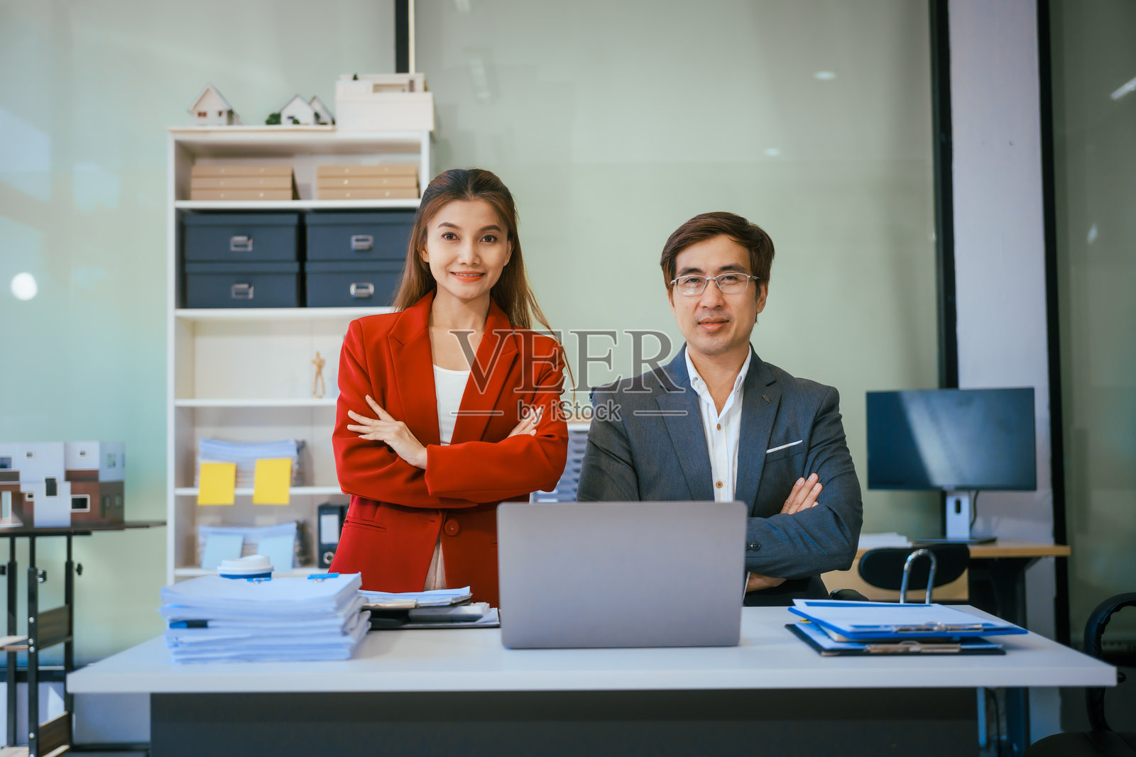 一位男商人和一位女商人在现代办公室的桌子旁坐着，微笑着讨论一个新项目或创业。他们在笔记本电脑上合作，专注于战略规划和团队合作。照片摄影图片