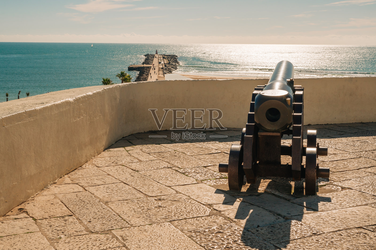 炮指向码头、沙滩和阳光明媚的海洋。照片摄影图片