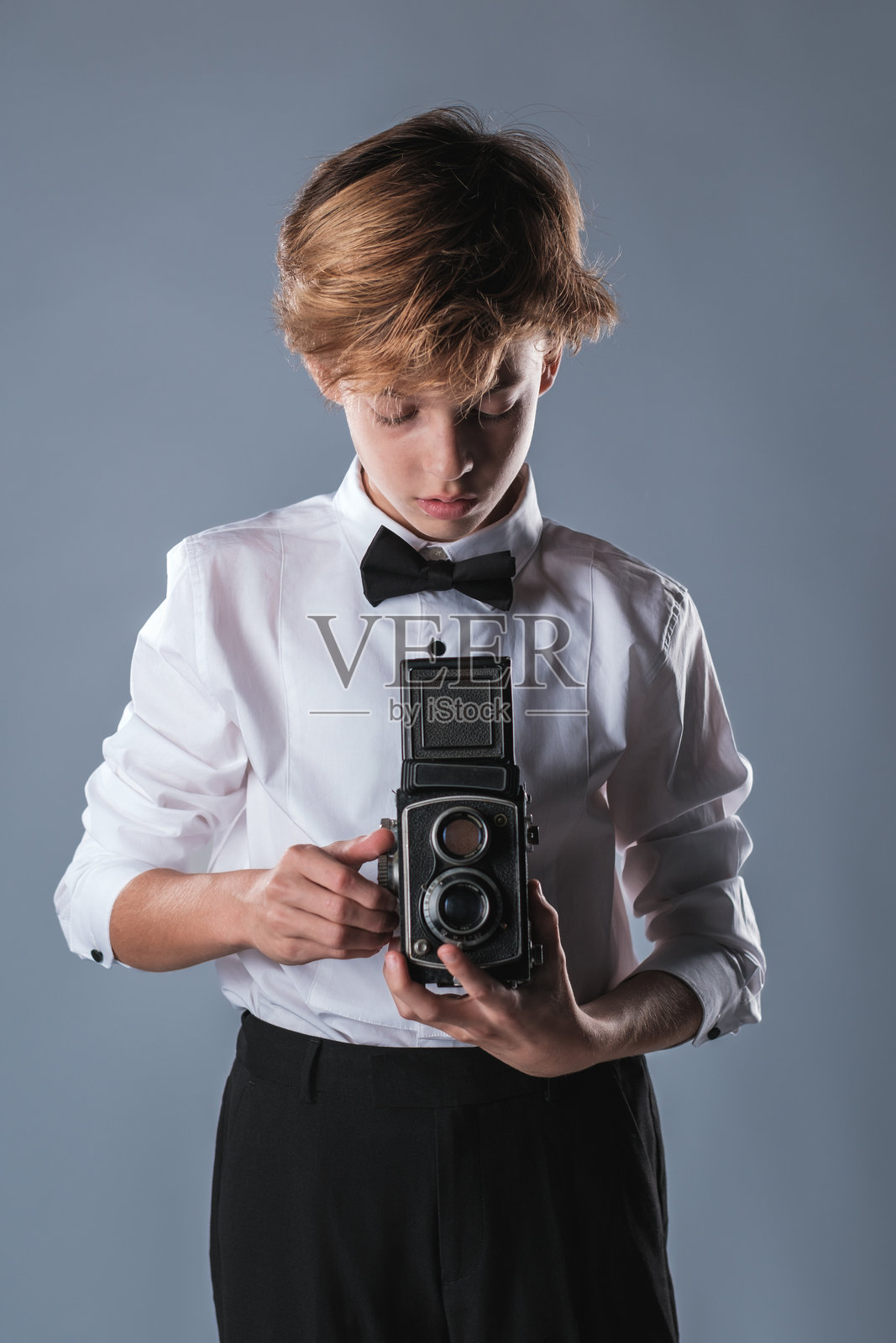 穿着白衬衫和领结的少年男孩手持复古相机照片摄影图片
