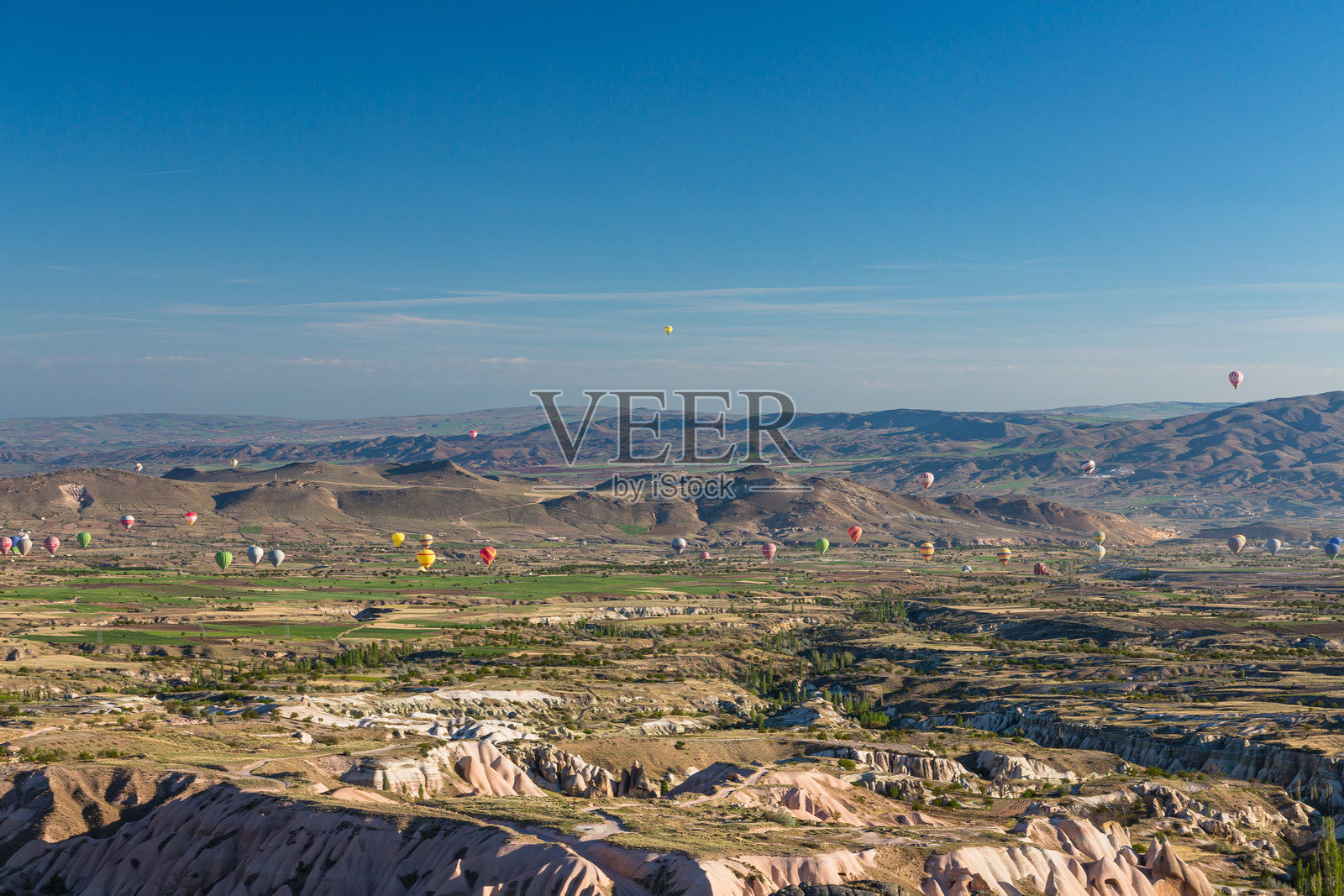 热气球在土耳其卡帕多奇亚的乌奇希萨尔城堡俯瞰的戈雷梅国家公园的晨空中飞行照片摄影图片