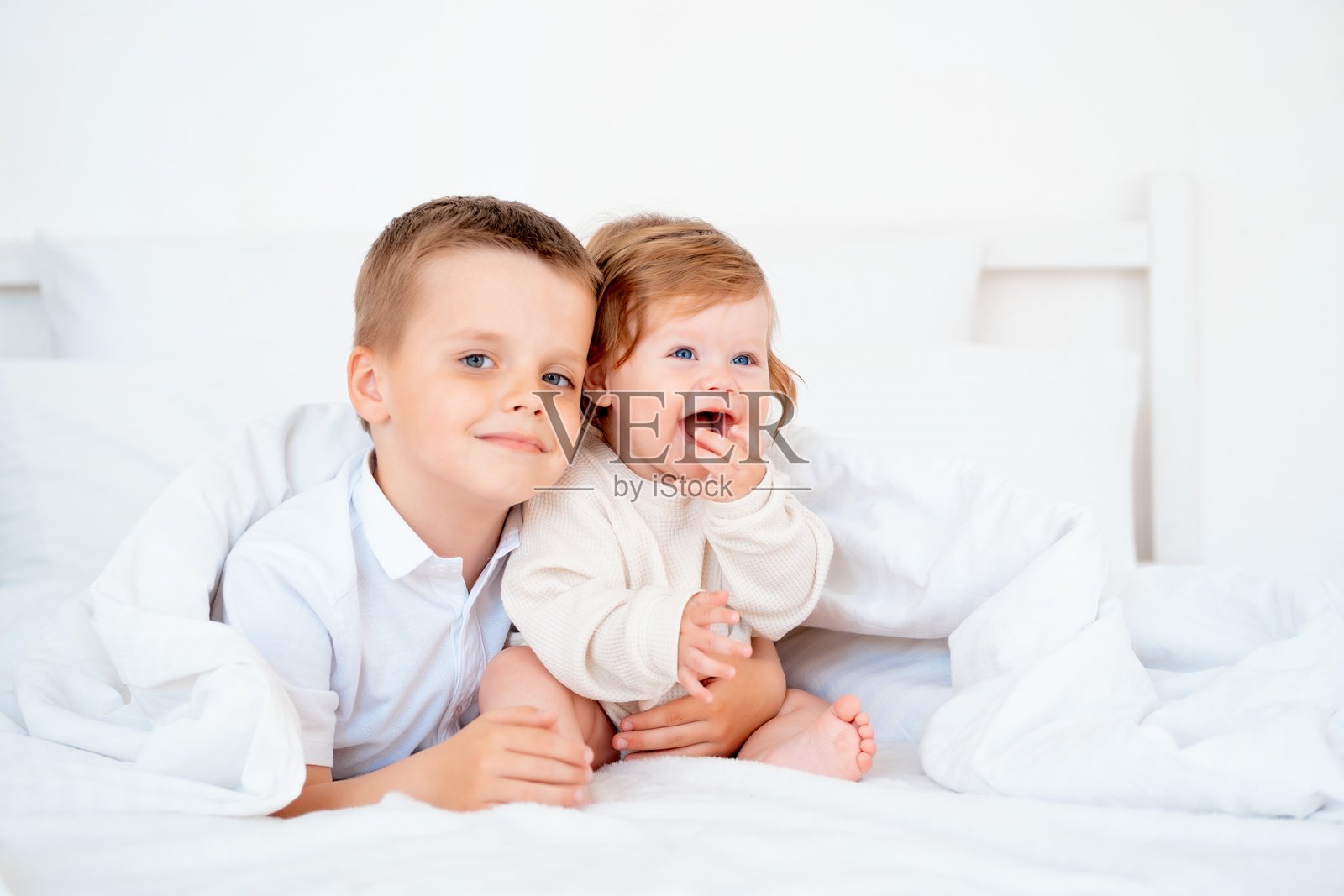 哥哥拥抱微笑的弟弟，兄弟之爱与关怀，两个孩子在床上的特写镜头照片摄影图片