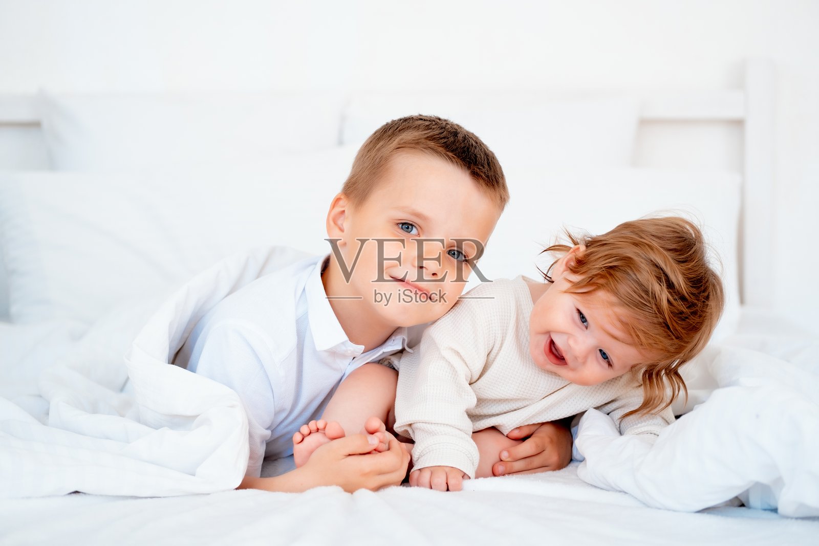 哥哥拥抱微笑的弟弟，兄弟之爱与关怀，两个孩子在床上的特写镜头照片摄影图片