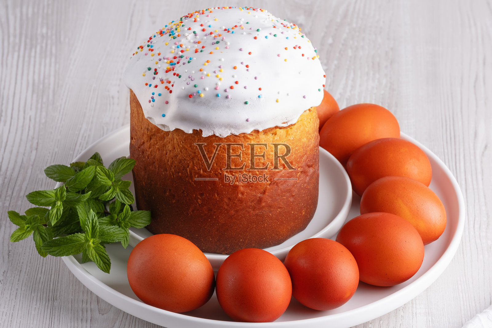 传统复活节面包与装饰红蛋和薄荷叶一起摆放在白色盘子上照片摄影图片