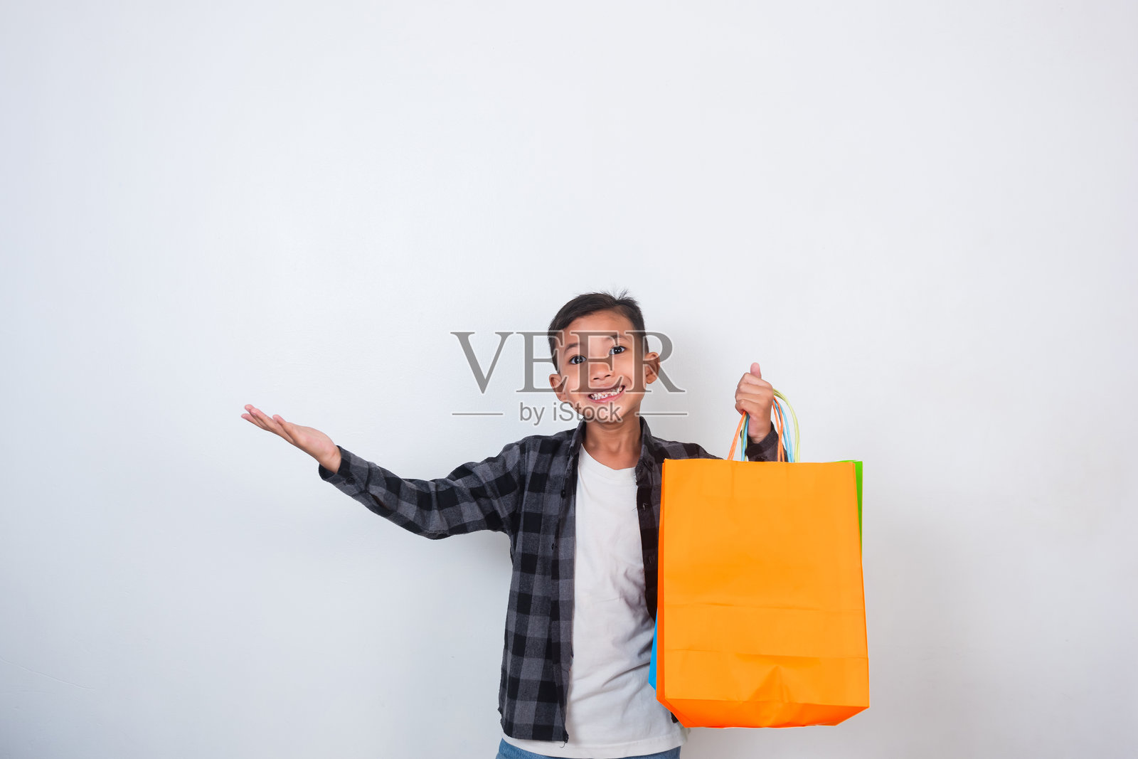 快乐帅气的亚洲男孩手拿购物袋，背景为白色。照片摄影图片