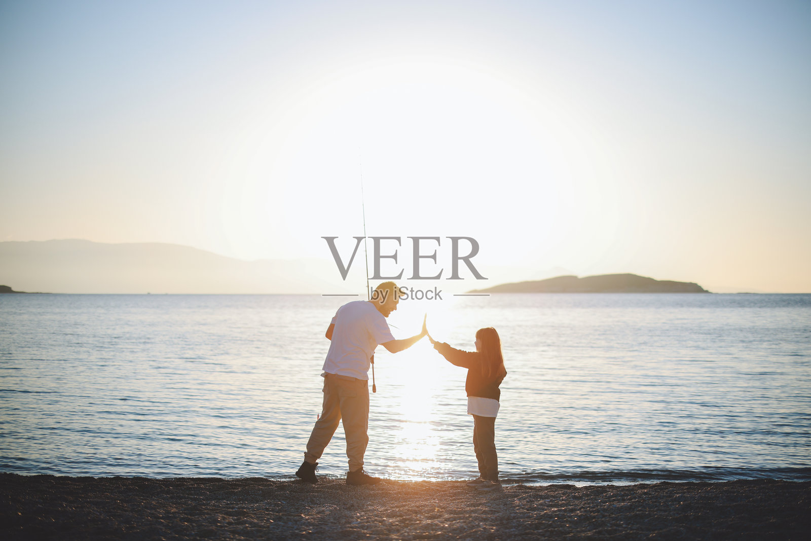 一位年轻父亲带着他的小女儿在海边钓鱼照片摄影图片