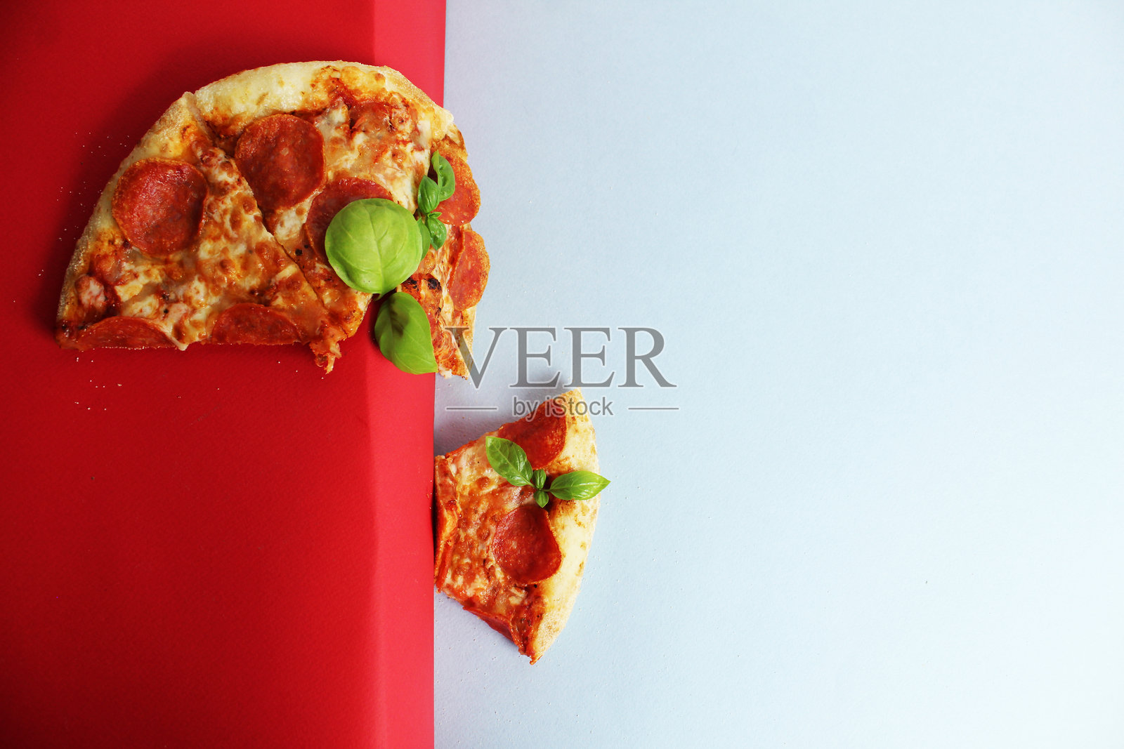 红白背景上的披萨片与罗勒。飞翔的披萨照片摄影图片