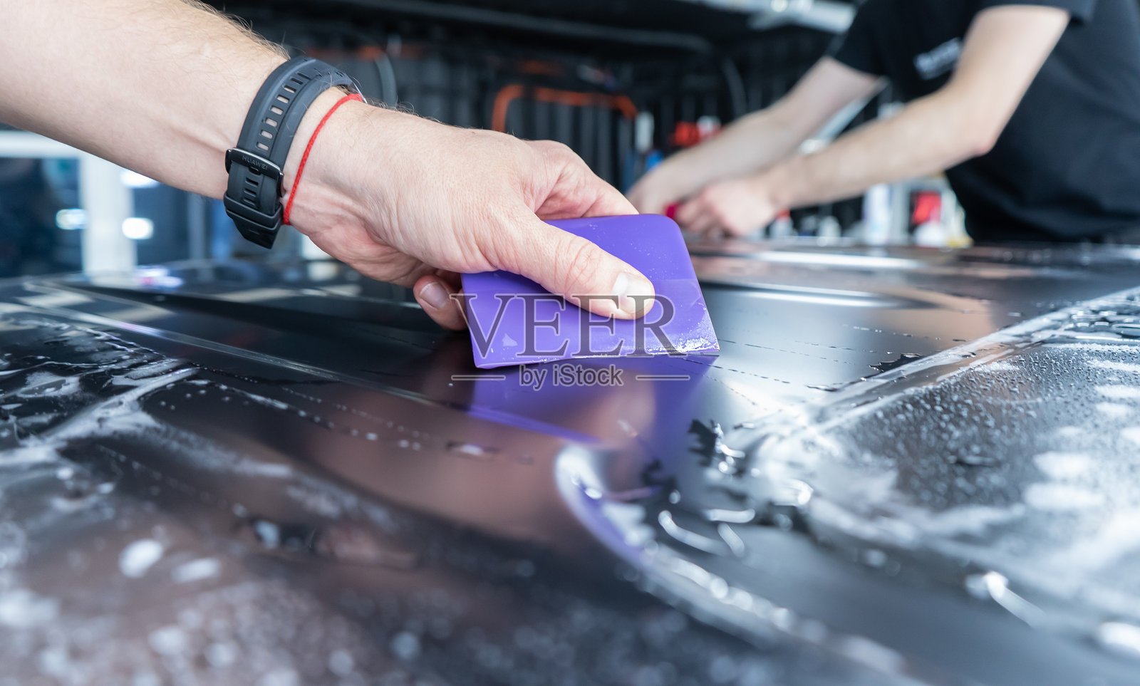 一位专注于用灰色哑光乙烯基或保护膜包裹汽车的专家正在工作。汽车包裹、调校、造型。照片摄影图片