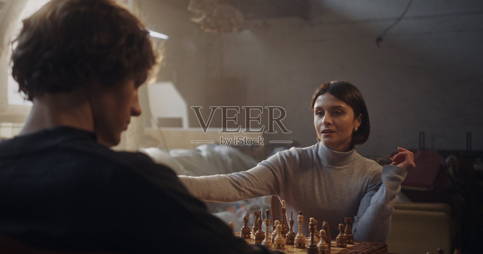 女性在阴郁的室内进行战略性的国际象棋移动照片摄影图片