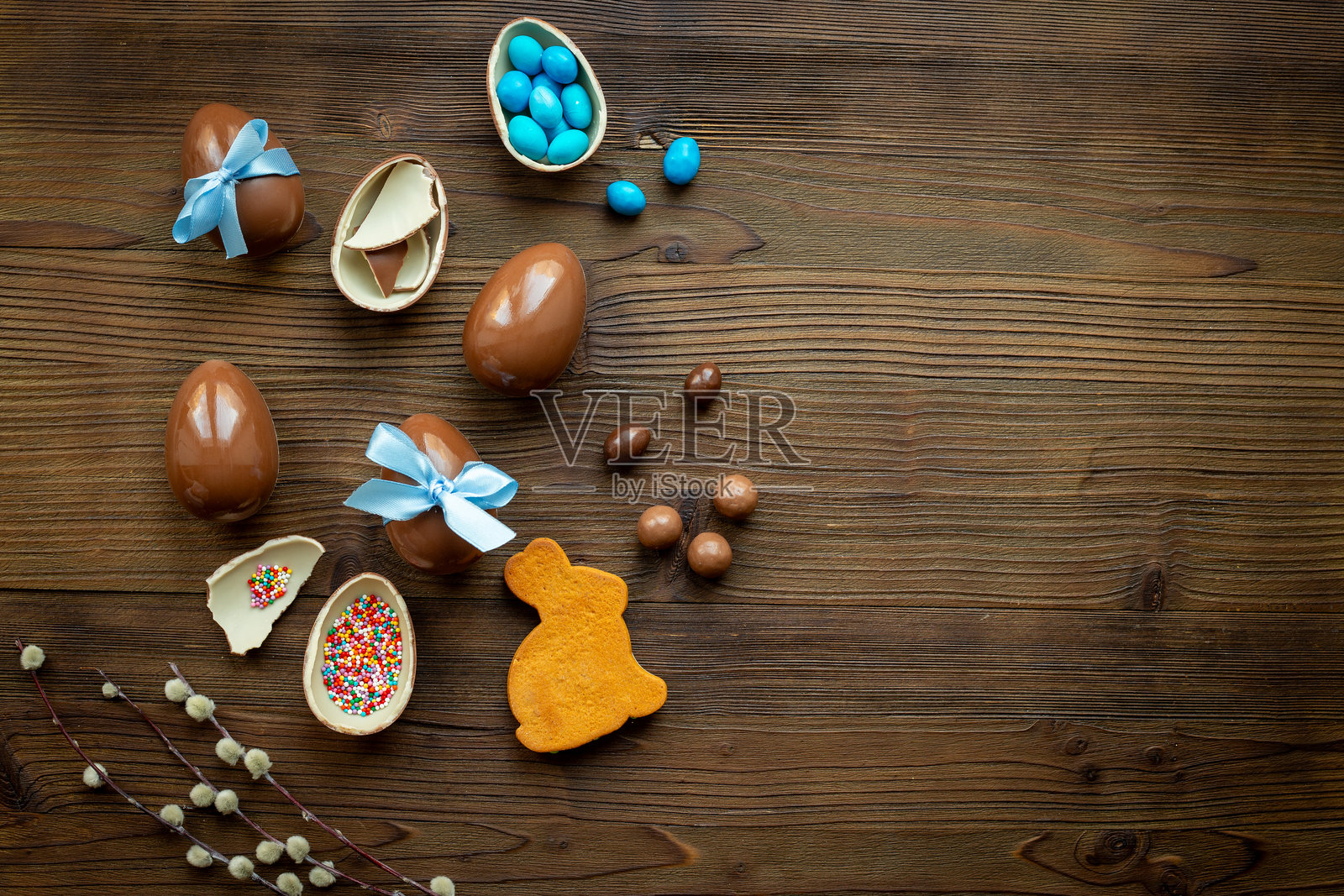 从上方俯视一堆带蓝色丝带的巧克力复活节彩蛋，背景为木质表面照片摄影图片