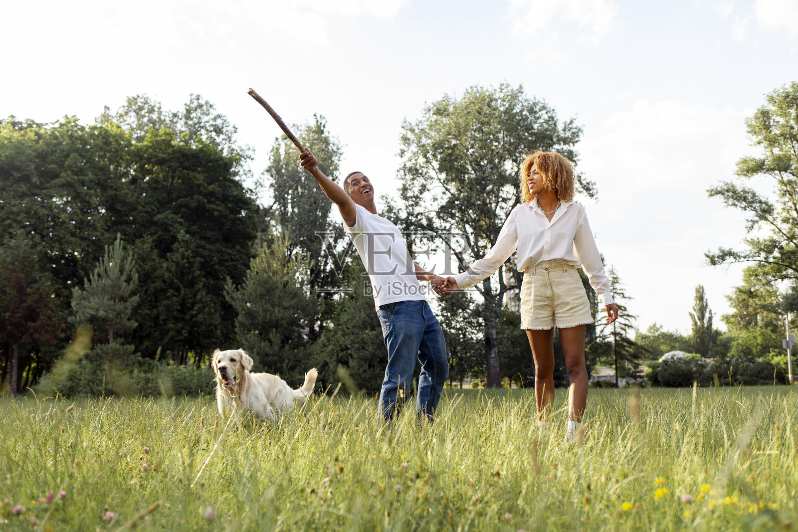 非裔美国人快乐的情侣在夏天的公园里一起散步和跑步，带着狗。照片摄影图片