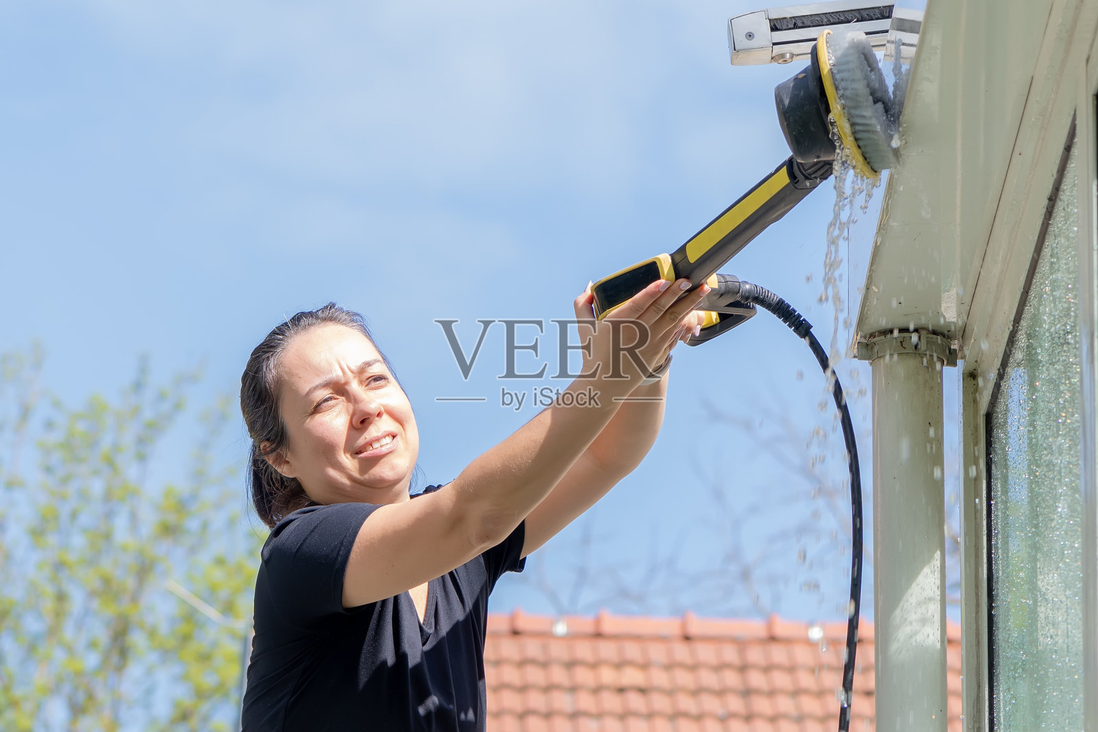 使用专业设备的女性在街上清洁玻璃。照片摄影图片