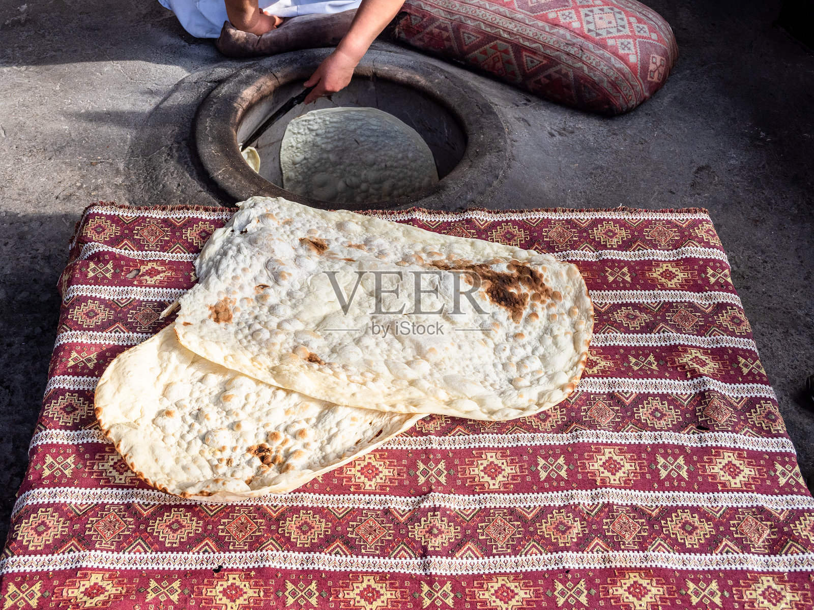 女人从坦杜尔的墙上剥下烤好的拉瓦什。照片摄影图片