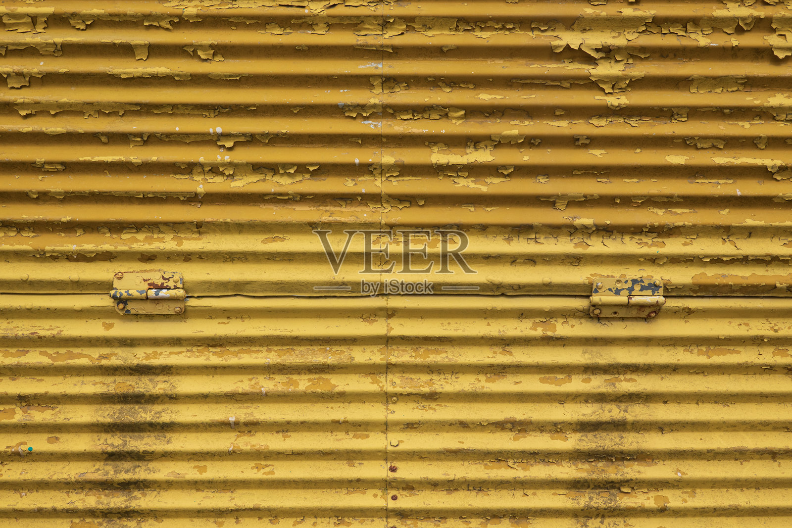 旧金属墙的碎片。波纹钢板用铆钉和铰链连接。黄漆部分鼓了起来，脱落了。背景。纹理。照片摄影图片