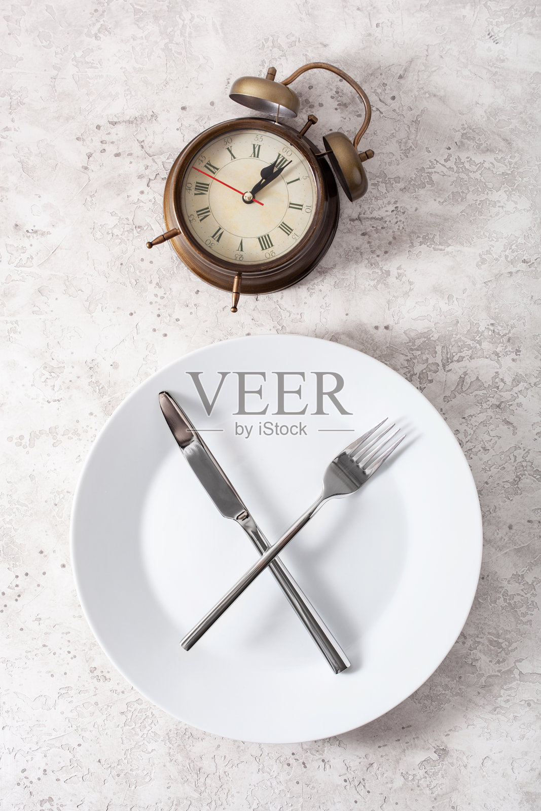 间歇性禁食的概念，生酮饮食，减肥。刀叉，盘子上的闹钟照片摄影图片