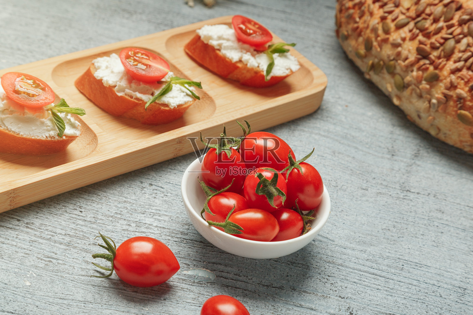 由新鲜的法棍面包、奶油奶酪、西红柿和绿色植物制成的健康小吃。照片摄影图片