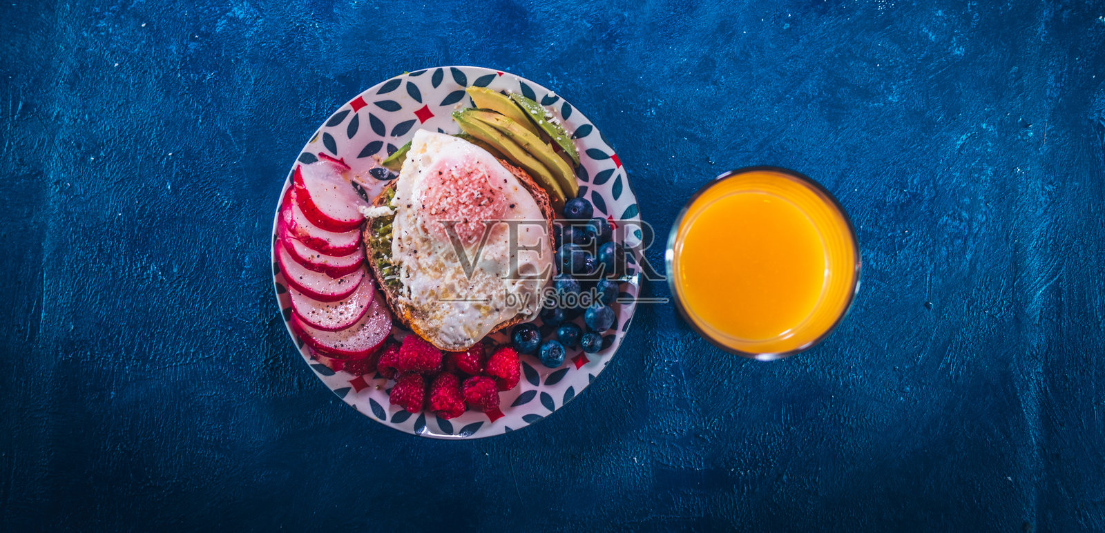 一杯咖啡和健康的早餐，深蓝色的背景。健康与咖啡的概念。牛油果，蓝莓，萝卜，水煮蛋，平铺，俯视图。天然肥胖斗士照片摄影图片