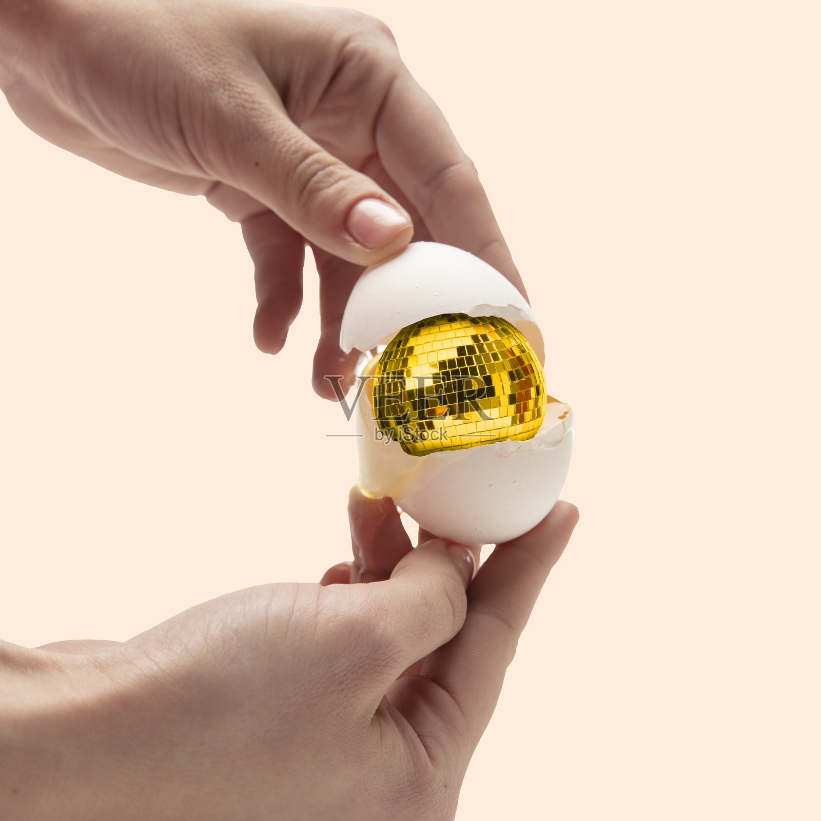 当代艺术拼贴。用手打开鸡蛋，里面有金色的迪斯科球作为蛋黄。一些令人眼花缭乱和意想不到的东西的诞生，比如革命性的想法或隐藏的才能。照片摄影图片