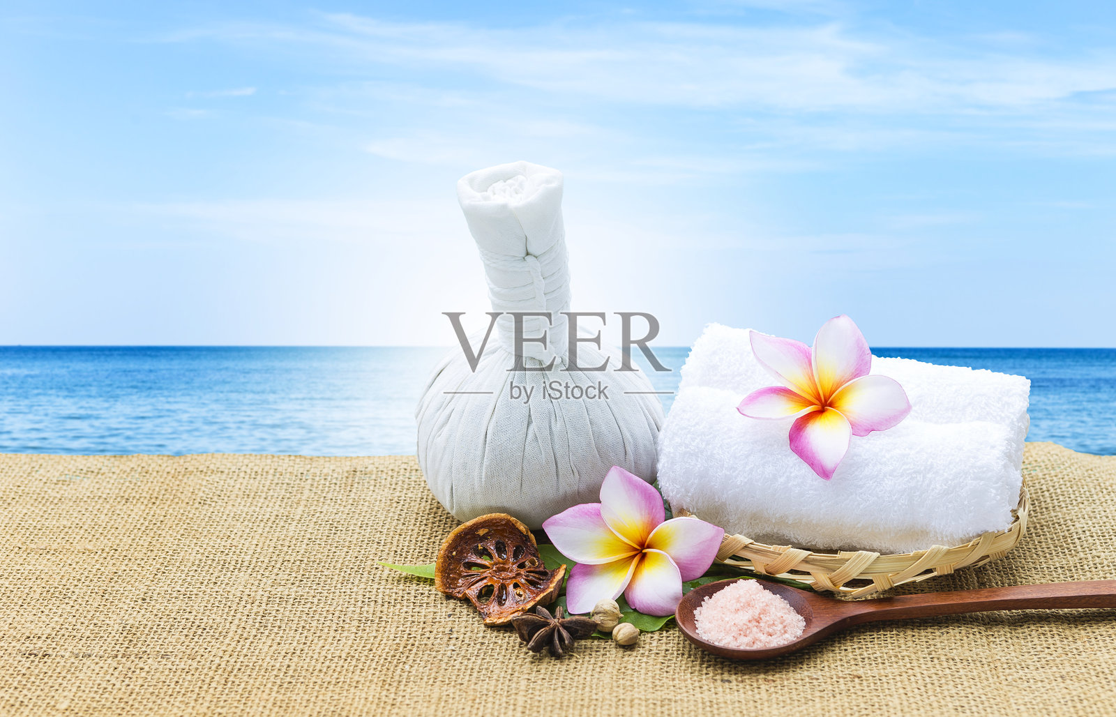 香草按摩球与干香草和粉红色的盐在木勺在模糊的热带海滩背景照片摄影图片