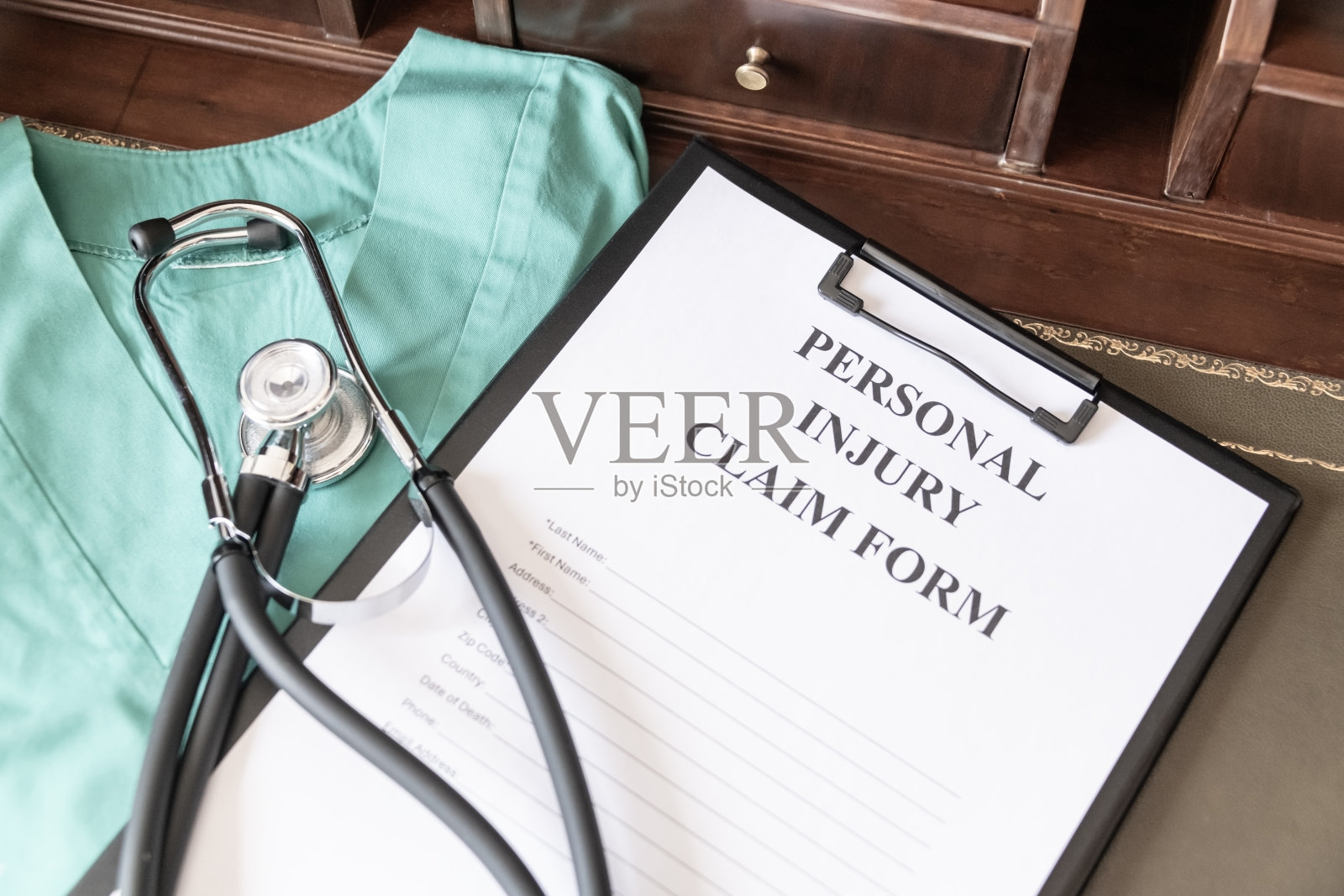 写在剪贴板上的人身伤害索赔表格，附有听诊器和医疗擦洗布，表明与健康有关的法律诉讼。照片摄影图片