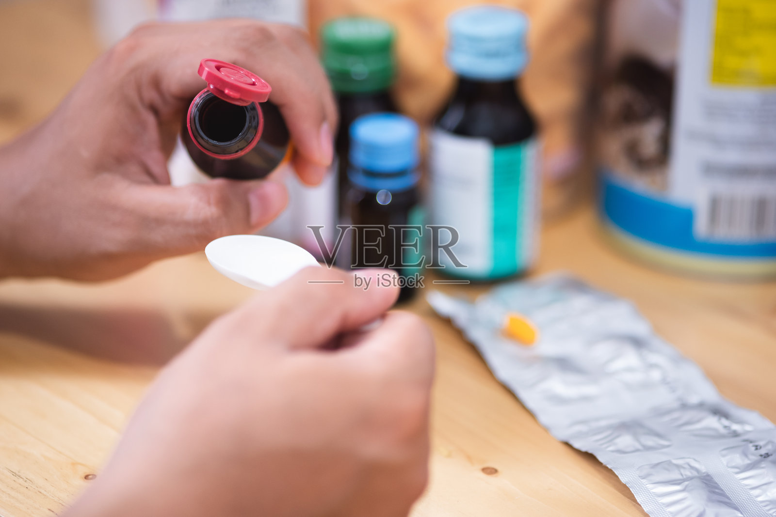 亚洲男子把止咳糖浆倒进勺子里喝。医疗、药学和保健理念照片摄影图片