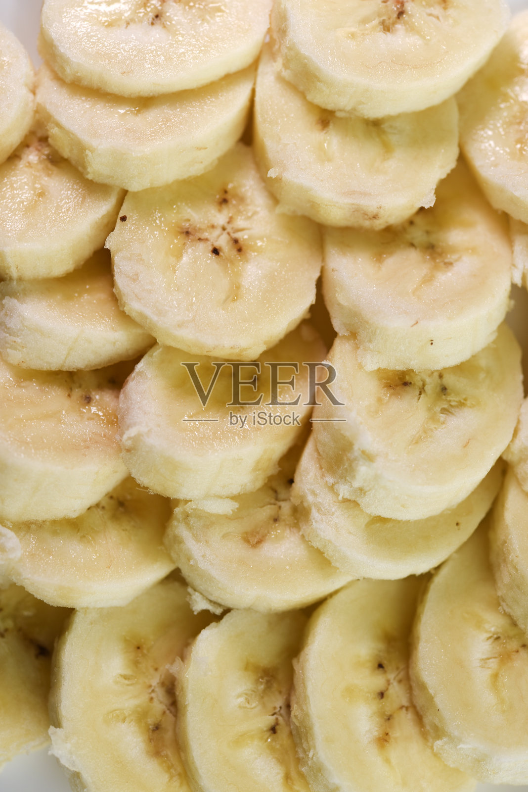 切成薄片的香蕉放在白色盘子里。美味多汁的水果。早餐在盘子里。照片摄影图片