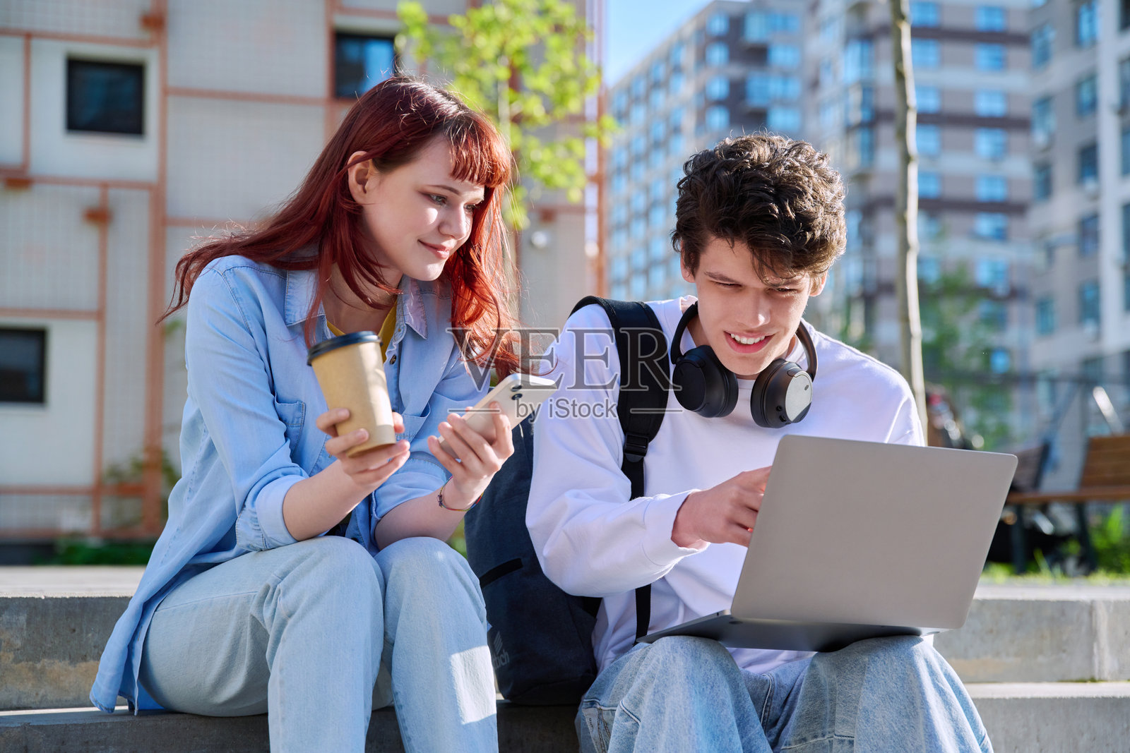 十几岁的大学生男生和女生聊天，坐在户外教育大楼附近照片摄影图片
