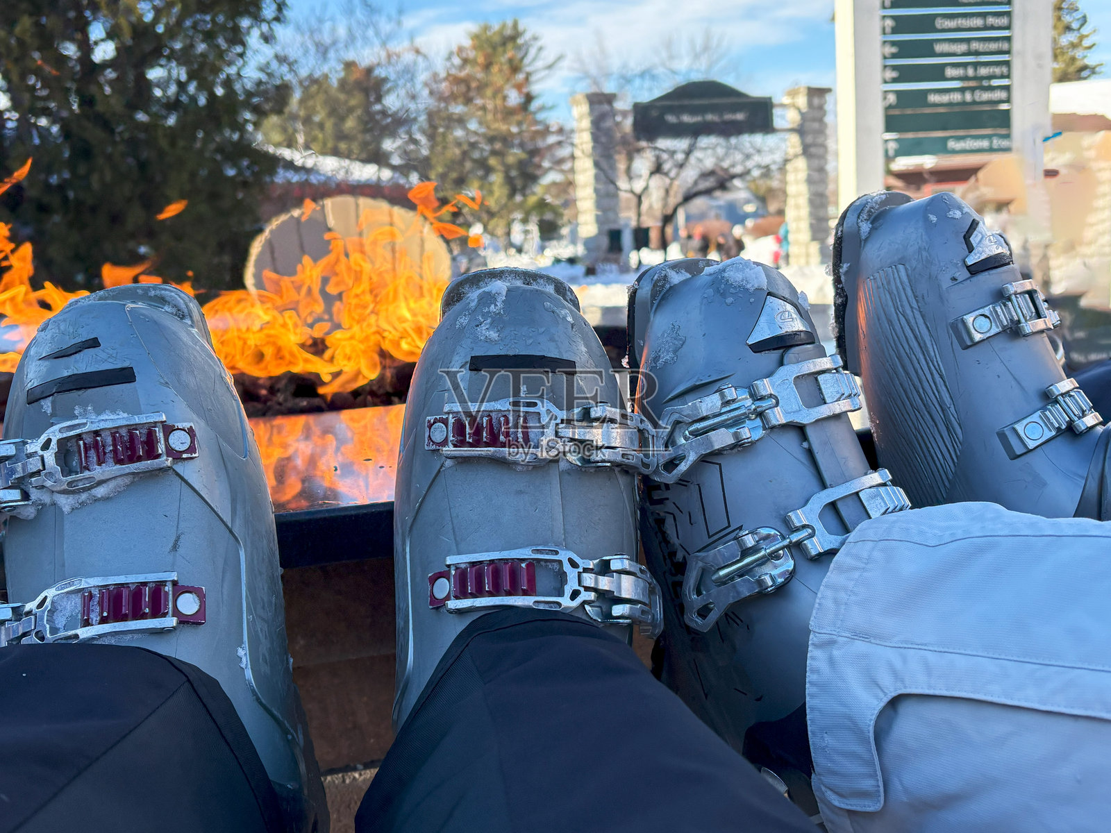 一群人在冬季滑雪度假村的火炉旁享受温馨时刻，靴子展示在一旁。照片摄影图片