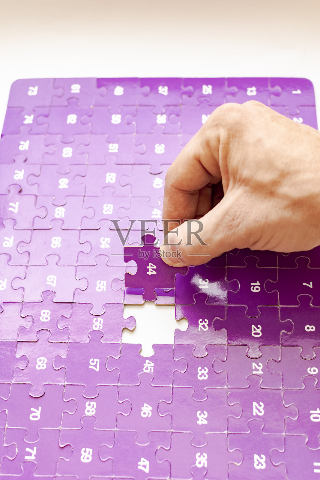 紫色拼图块，上面有白色数字，手握着数字44。照片摄影图片
