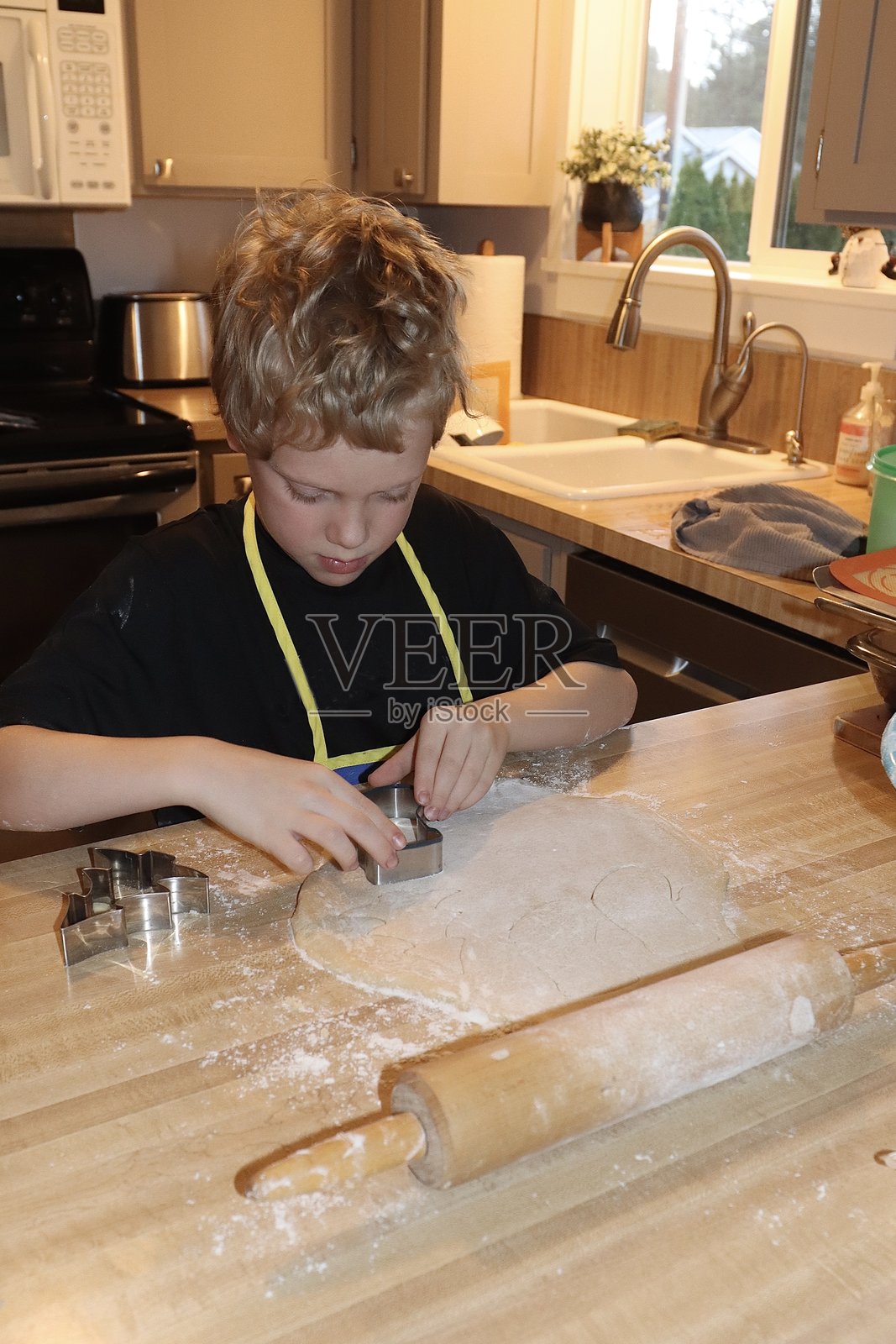 年轻人在厨房里切割糖饼干照片摄影图片